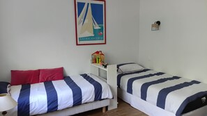 A room with two beds, a small table with toys, a lamp, and a framed picture on the wall. - Cap Ferret maison familiale, plage à 5 mn et proche des commerces. (Lège-Cap-Ferret)