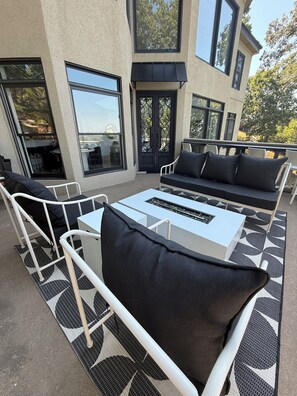 An outdoor seating area with a white table, black cushions, and a patterned rug. - Gorgeous Lakefront 5 bedroom with Stunning Views (Rogers)