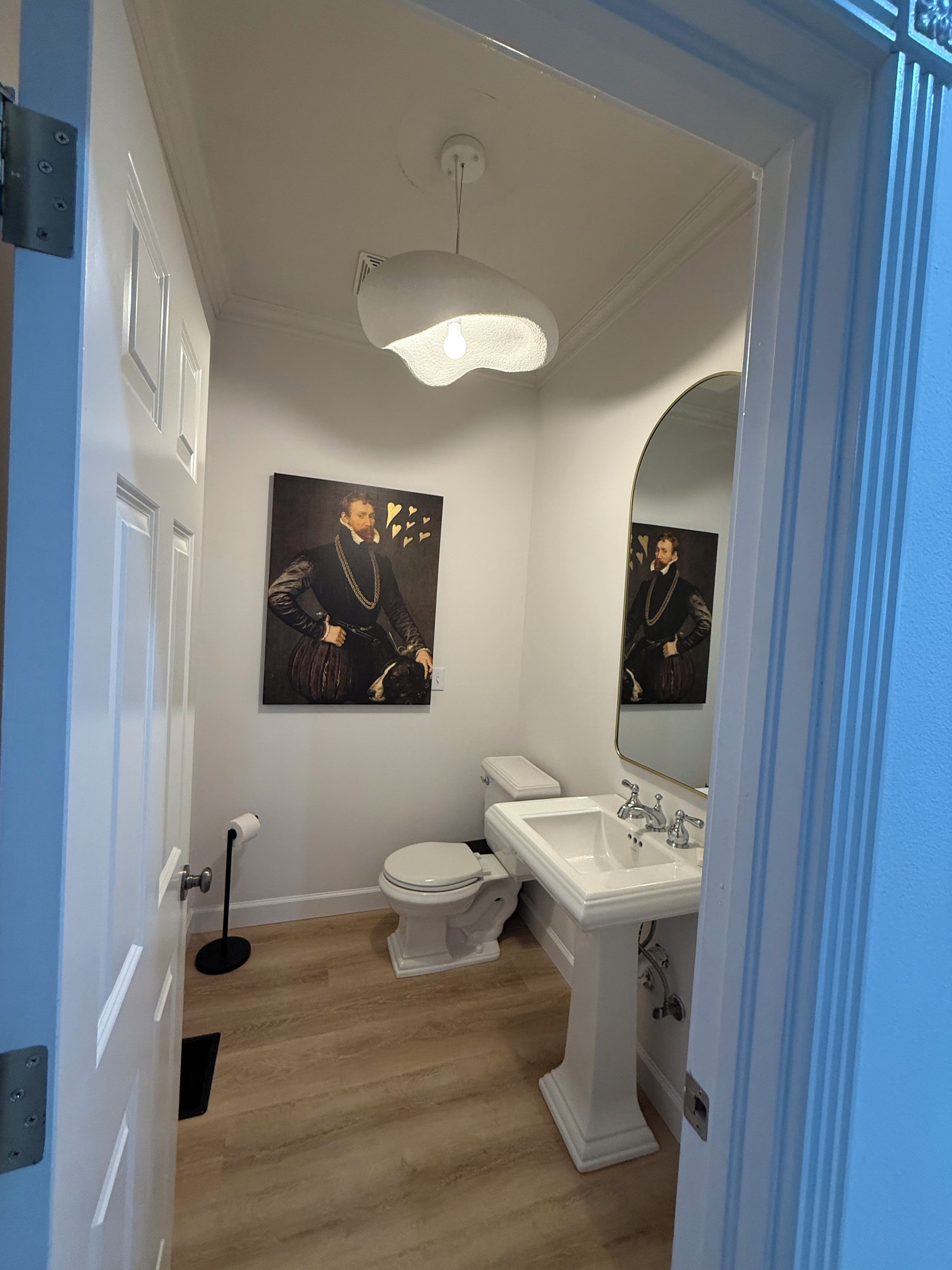 Un baño con inodoro, lavamanos y un cuadro en la pared.