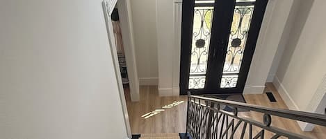 Una escalera con barandilla, escalones alfombrados y una puerta con un panel de vidrio decorativo.