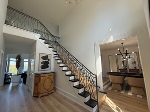 A spacious living area with a staircase, a wooden cabinet, and a seating area with chairs. - Gorgeous Lakefront 5 bedroom with Stunning Views (Rogers)