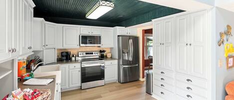 Una cocina con armarios blancos, electrodomésticos de acero inoxidable y piso de madera.