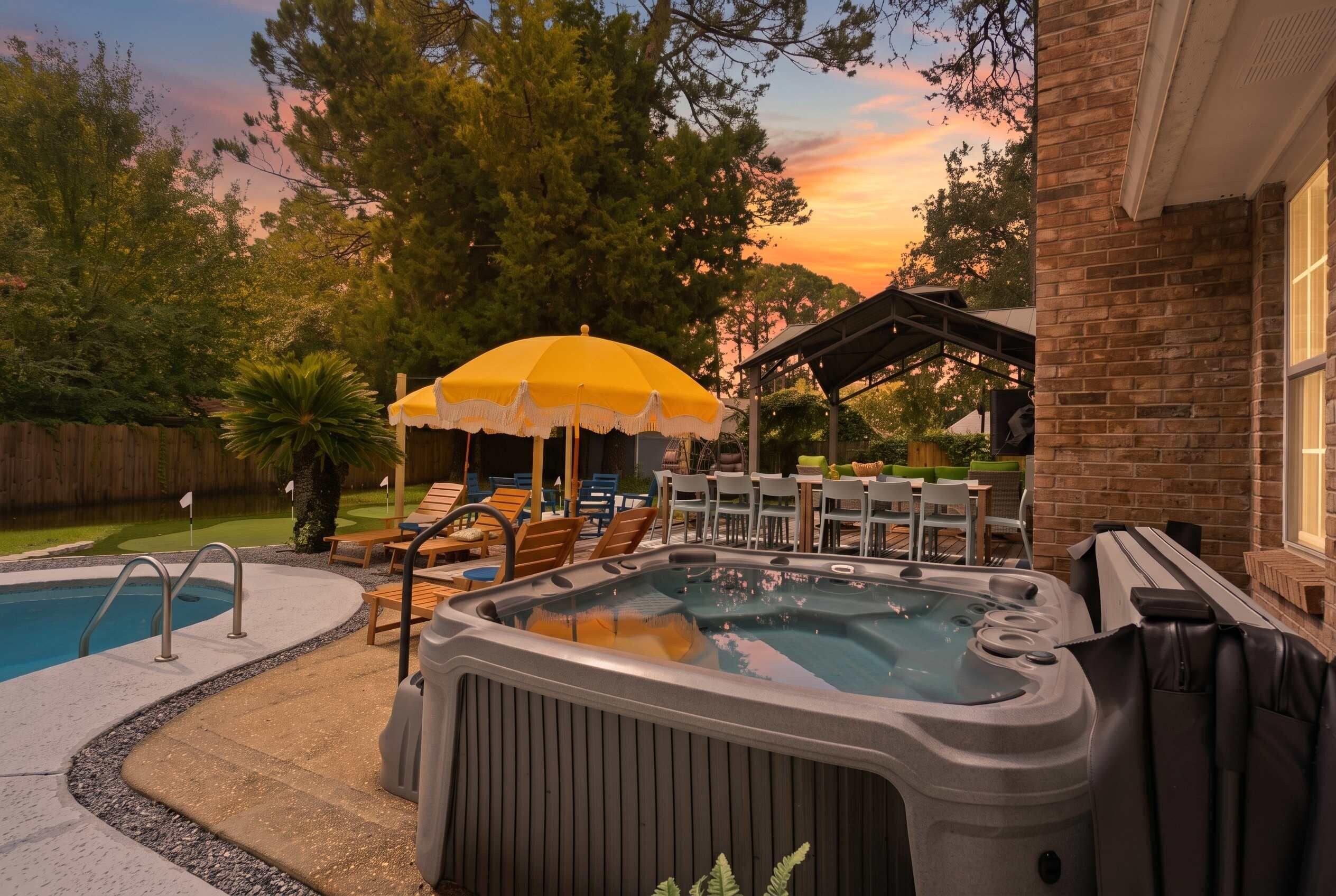 Un jardin avec un jacuzzi, des chaises longues et une piscine.