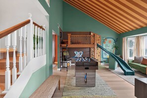 A spacious living area with a foosball table, a slide, and a lofted play area. - 4BR Emerald Coast Escape | Pool, Hot Tub & Theater (Fort Walton Beach)