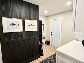 A bathroom with a black vanity, a white sink, and framed fish pictures on the wall.