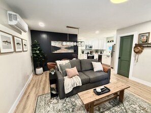 Un salon moderne avec un canapé, une table basse et une vue sur la cuisine.