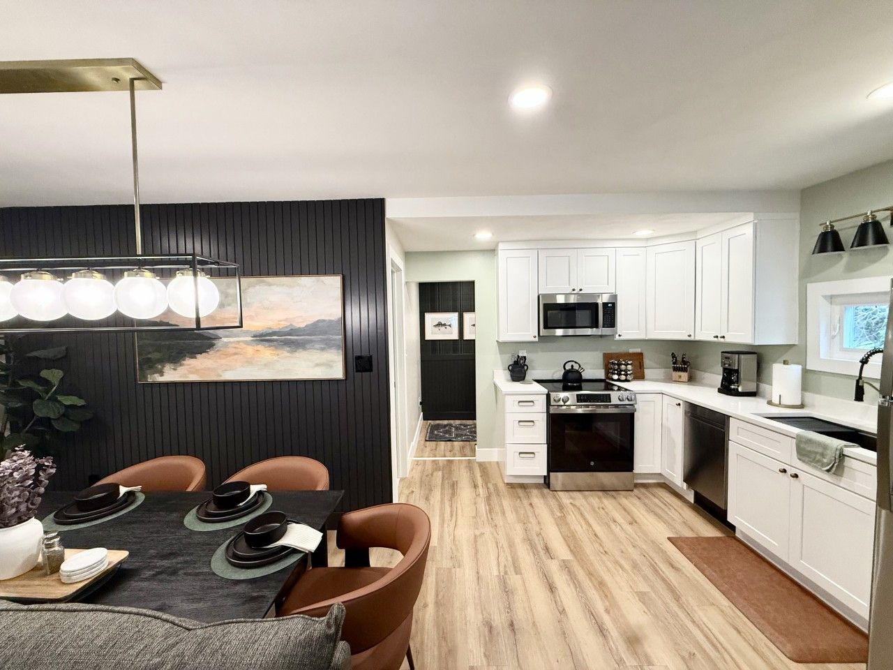 A modern kitchen with white cabinets, a black countertop, and a dining area with a table set for four.