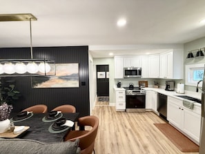 A modern kitchen with white cabinets, a black countertop, and a dining area with a table set for four.