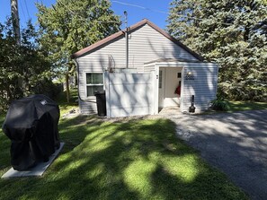 A single-story house with a garage, a covered grill, and a well-maintained lawn.