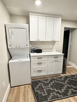 A compact kitchen with white cabinetry, a built-in oven, and a microwave.