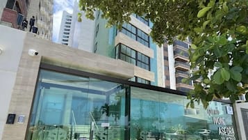 Un edificio moderno con amplios ventanales y un árbol en primer plano.