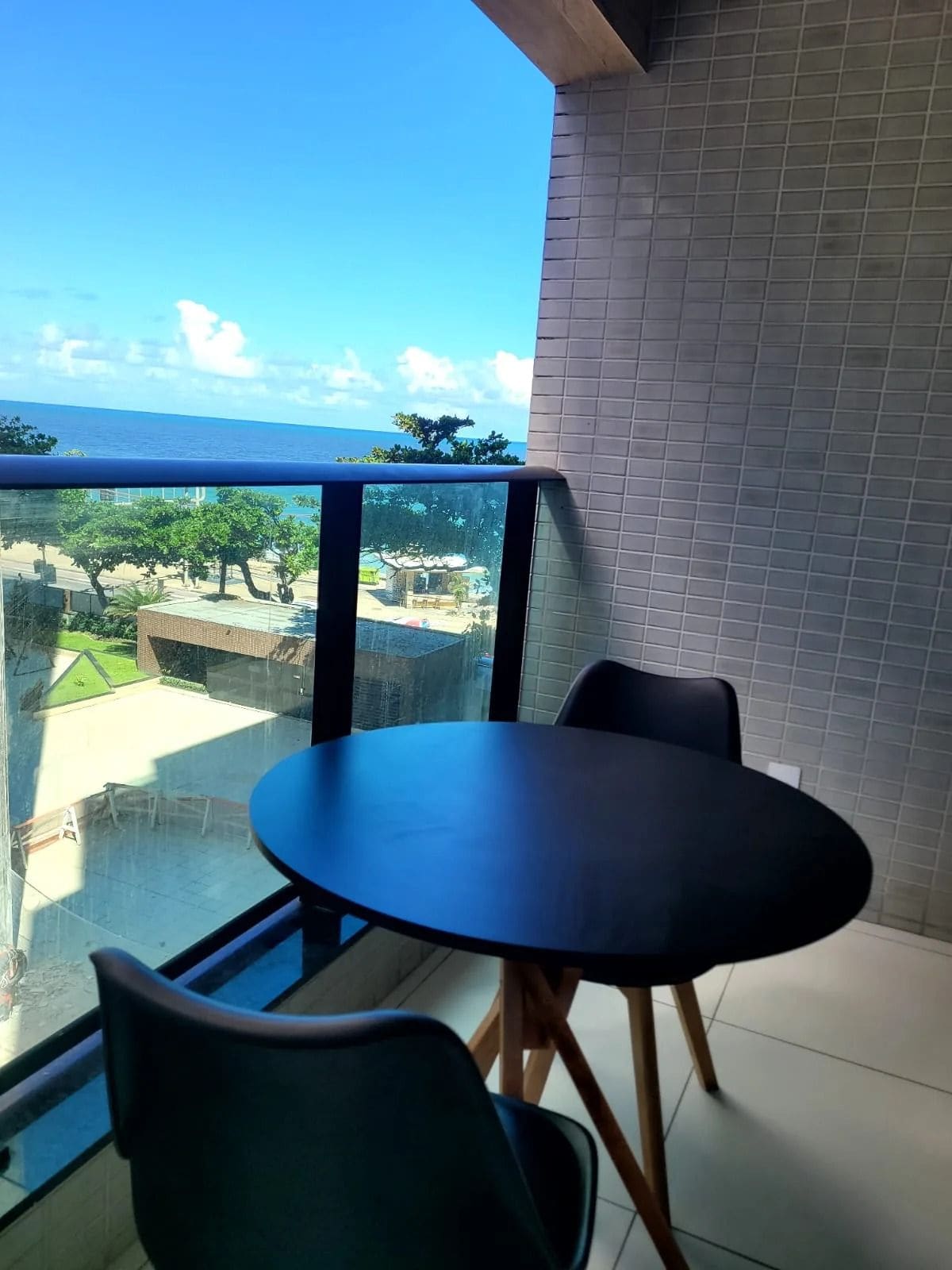 Un balcón con mesa y sillas, con vista al mar y edificios.