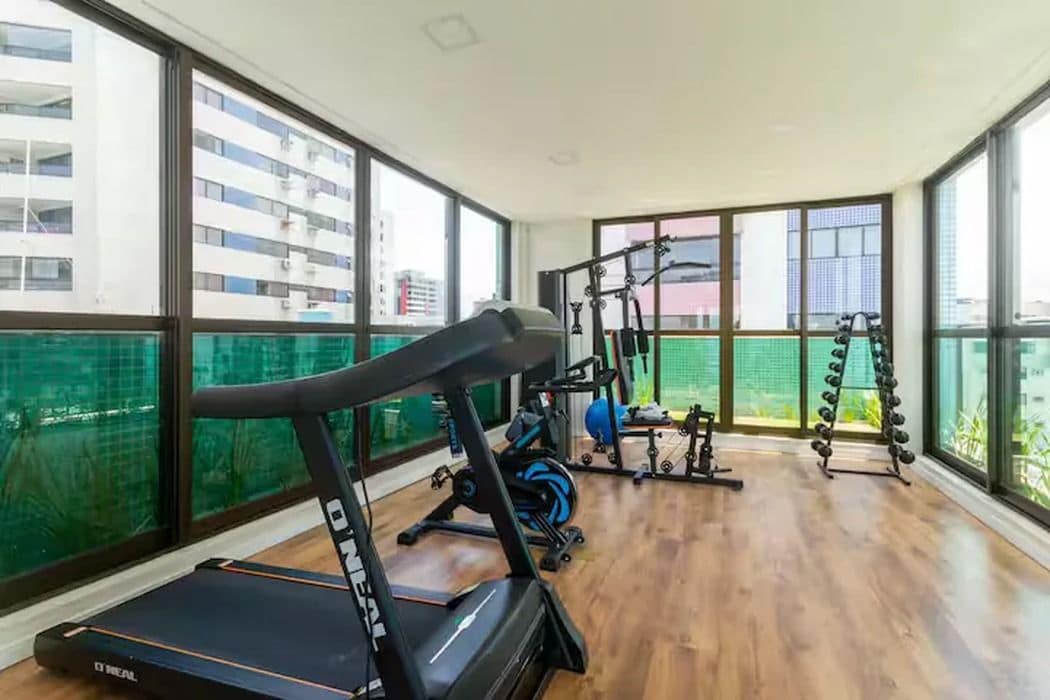 Un gimnasio con cintas de correr, máquinas de pesas y una máquina de remo.
