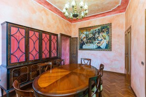 Ein Esszimmer mit einem großen Holztisch, Stühlen, einer Kandelaber und einem Gemälde an der Wand.