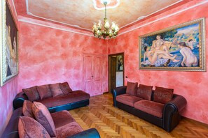 Ein Zimmer mit zwei Sofas, einem Kronleuchter und einem großen Gemälde an der Wand.