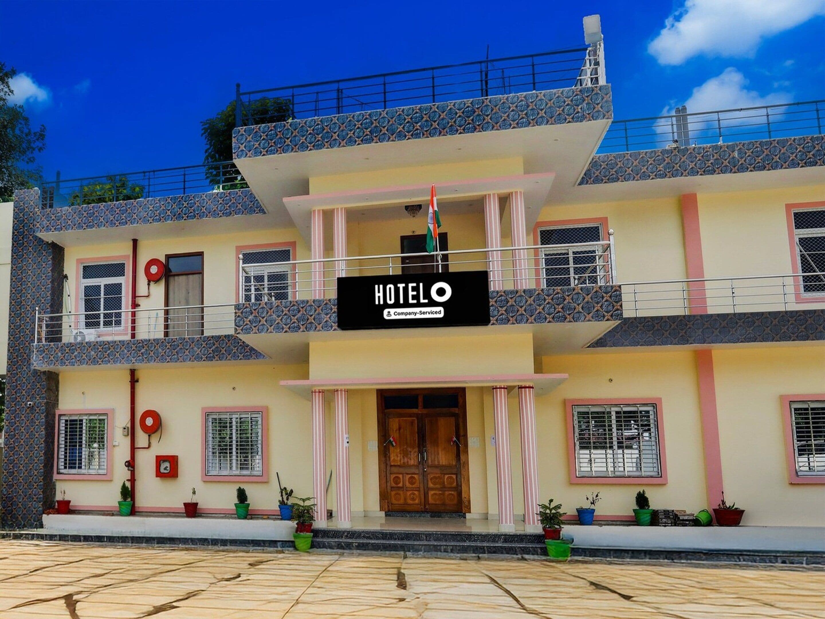 A two-story hotel with a balcony on the upper floor, a sign indicating it is company-serviced, and a flag.