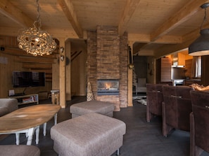 A cozy living room with a stone fireplace, wooden beams, and a television. - Cabin in Turrach With Sauna and Wi-fi (Stadl-Predlitz)