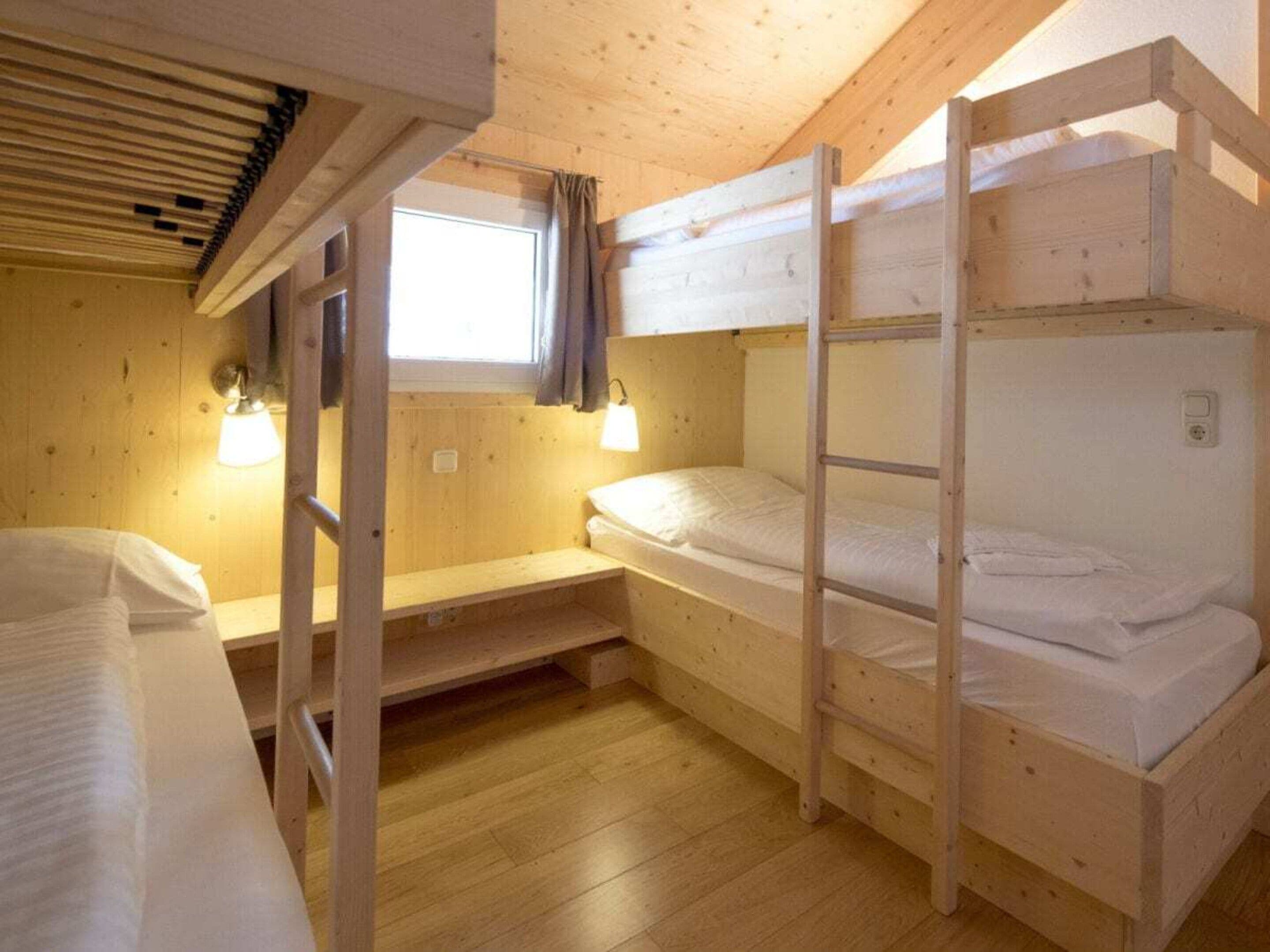 Una camera con letto a castello, una finestra, pareti e pavimento in legno.