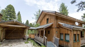 A wooden cabin with a covered porch and a gravel driveway. - Cabin in Turrach With Sauna and Wi-fi (Stadl-Predlitz)