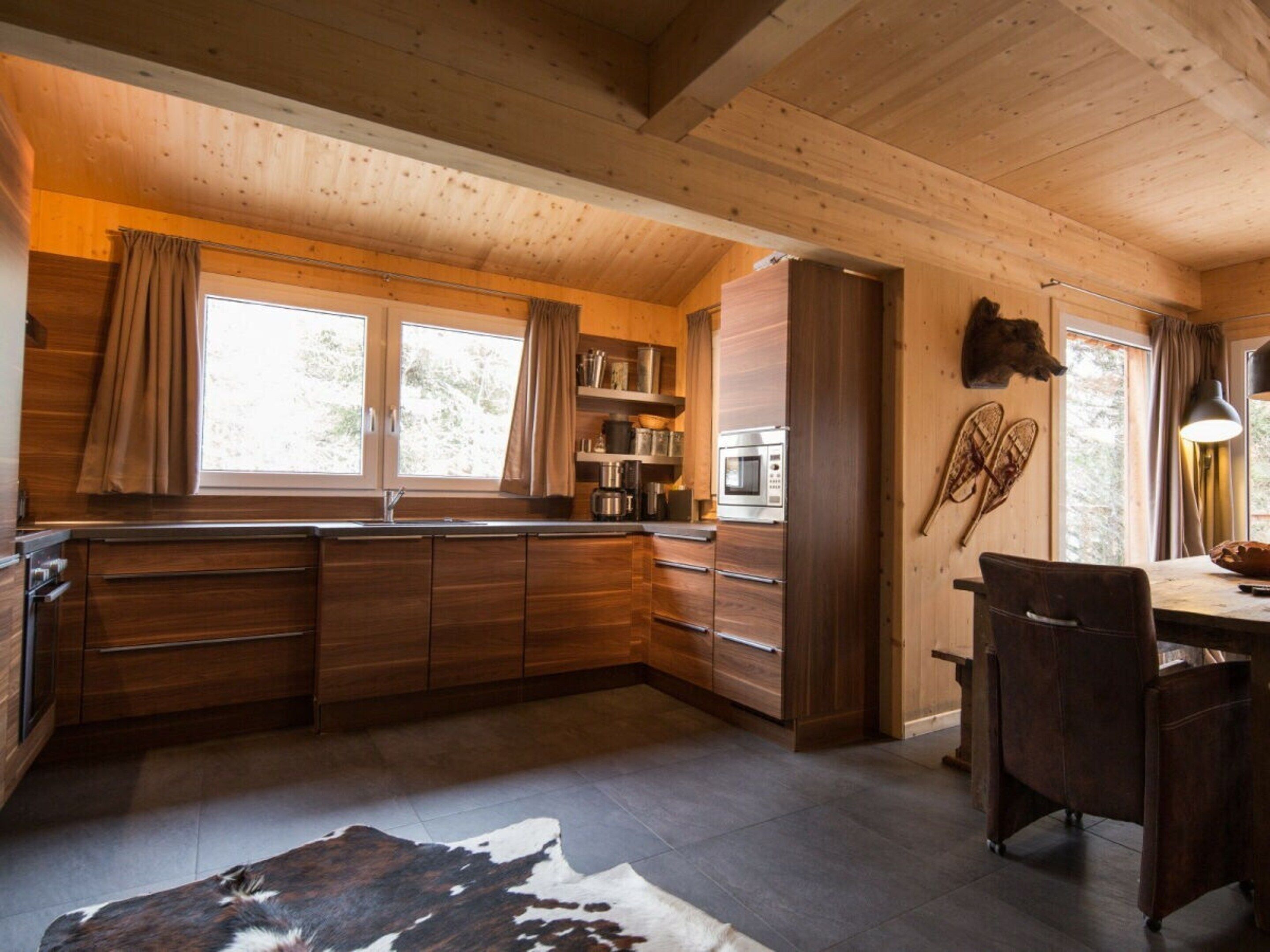 A wooden interior with a kitchen area, a dining table, and a chair.