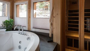 A wooden interior with a large bathtub, two windows, and a sauna door. - Cabin in Turrach With Sauna and Wi-fi (Stadl-Predlitz)