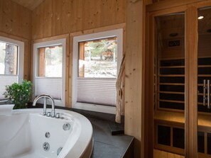 A wooden interior with a large bathtub, two windows, and a sauna door. - Cabin in Turrach With Sauna and Wi-fi (Stadl-Predlitz)