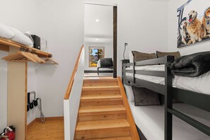 A modern bedroom with a wooden staircase, a bunk bed, a wooden shelf with towels, and a painting of dogs. - Sundancer Lodge - True Ski-In/Out+Hot Tub+Views (Mountain Village)