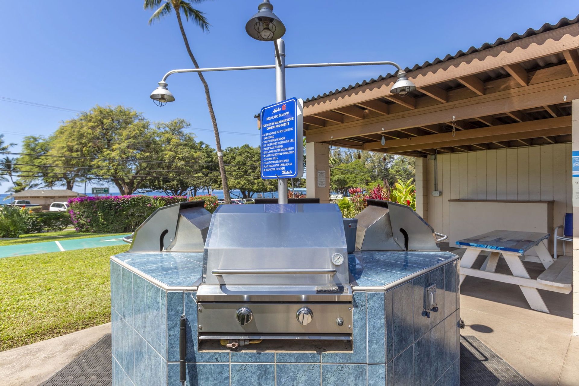 Ein Grillbereich im Freien mit einem Schild, das die Grillzeiten und Nutzungsregeln anzeigt.