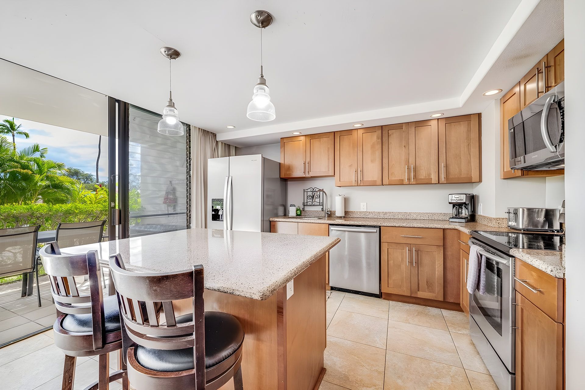 Une cuisine moderne avec des meubles en bois, des appareils en acier inoxydable et un grand îlot central doté de sièges.