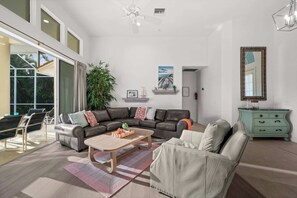 Een ruime woonkamer met een grote bank, een salontafel en een eethoek met stoelen.