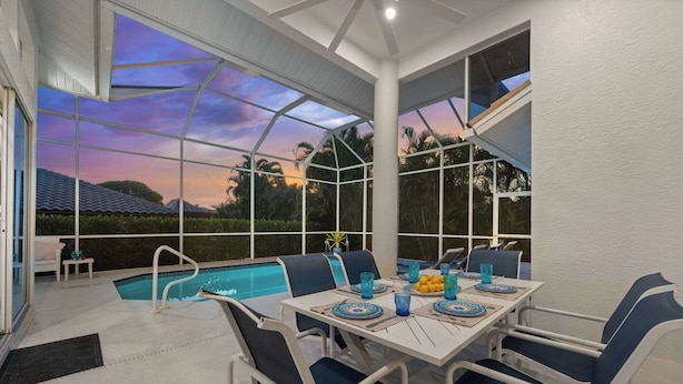An outdoor patio with a pool, dining table, and chairs. - Walk to the Beach from a 4-Bedroom Villa with Bikes and Beach Gear Included (Marco Island)