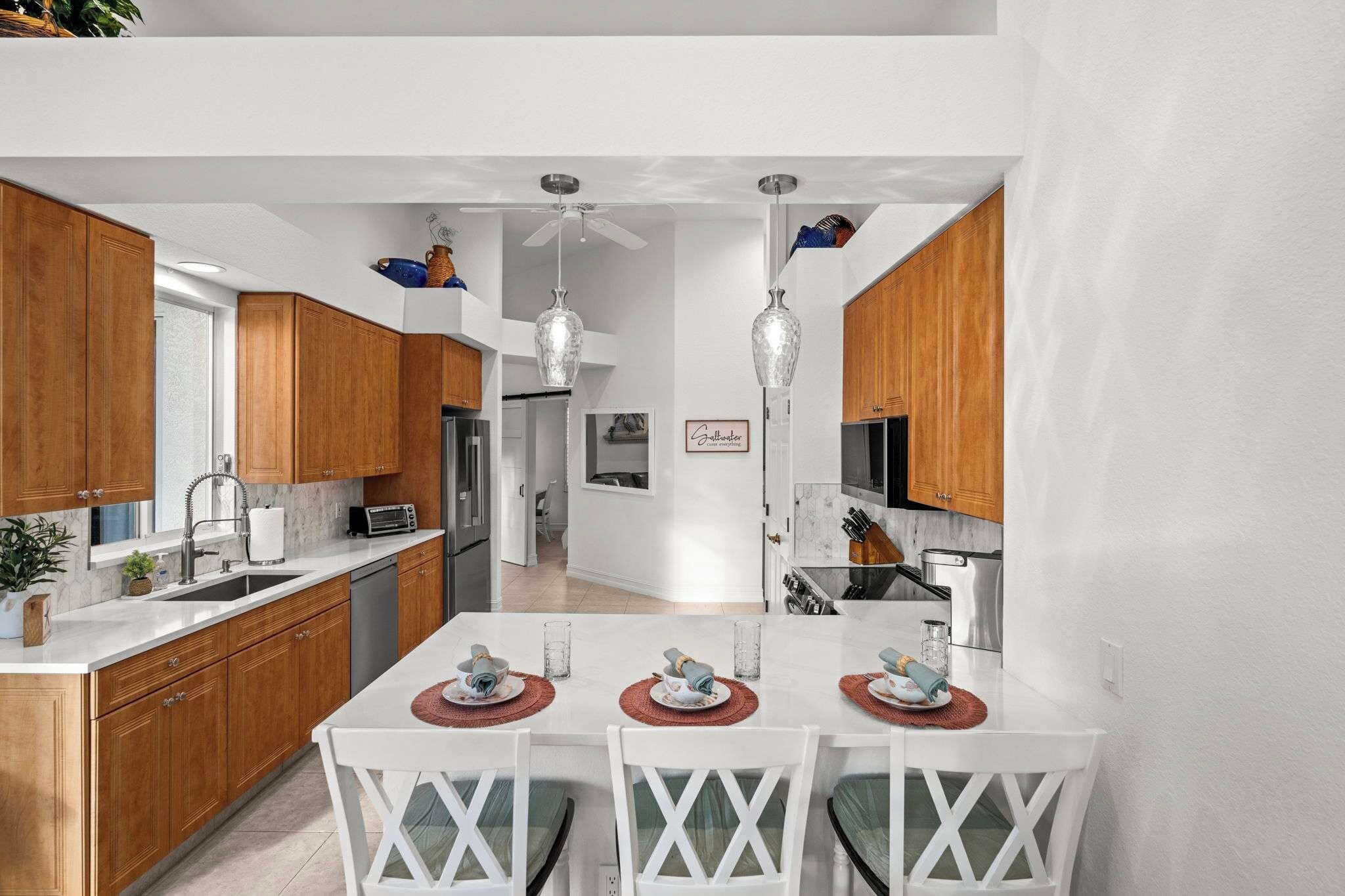 Una cocina moderna con armarios de madera, una mesa de comedor blanca y un ventilador de techo.