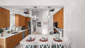 Una cocina moderna con armarios de madera, una mesa de comedor blanca y un ventilador de techo.