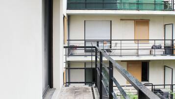 Un immeuble à plusieurs étages doté d’un balcon, d’une fenêtre avec un volet et d’une porte.