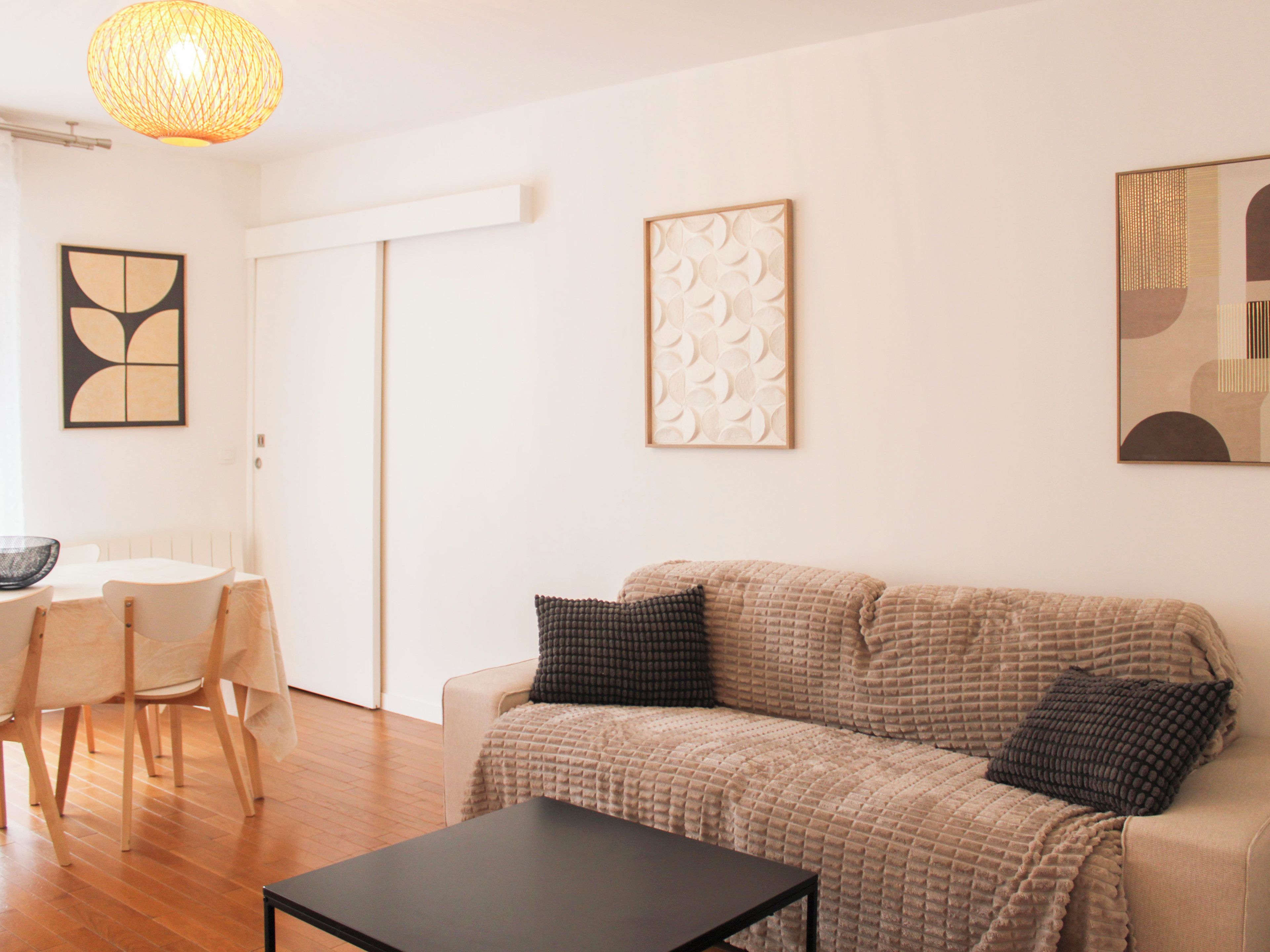 Un salon avec un canapé, une table et une chaise. Il y a des décorations murales et une porte.