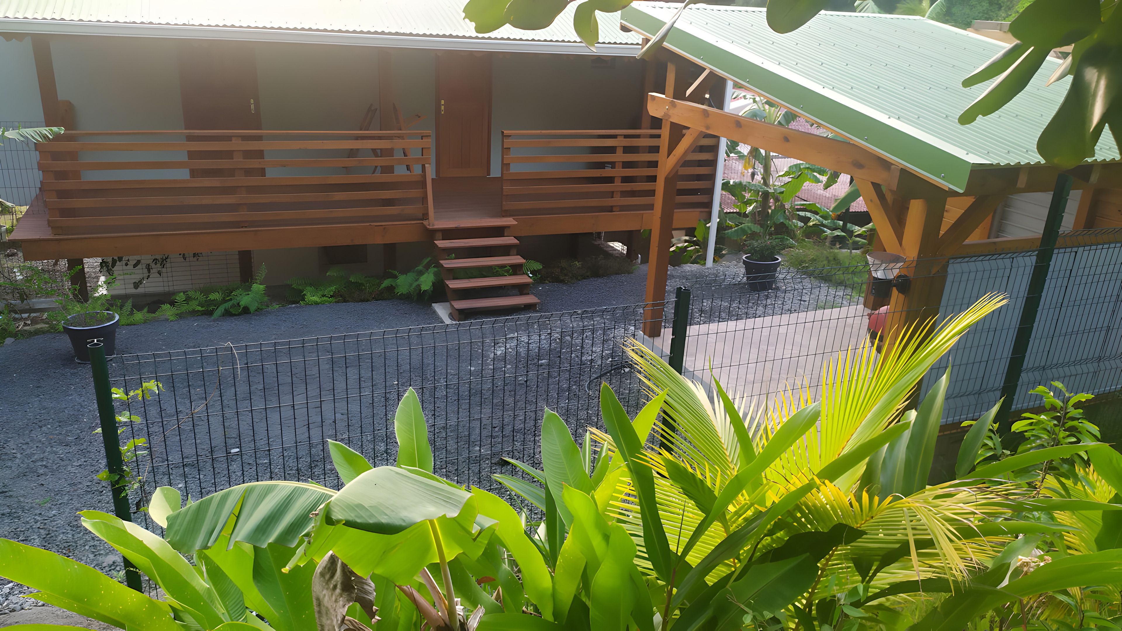 A covered outdoor area with a wooden deck, a staircase, and a fenced garden.