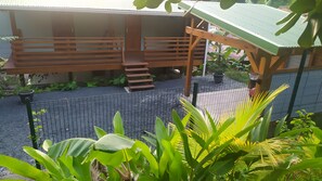 A covered outdoor area with a wooden deck, a staircase, and a fenced garden. - Apartment Milo: Mountain View, Wi-Fi, and Air Conditioning (Bouillante)