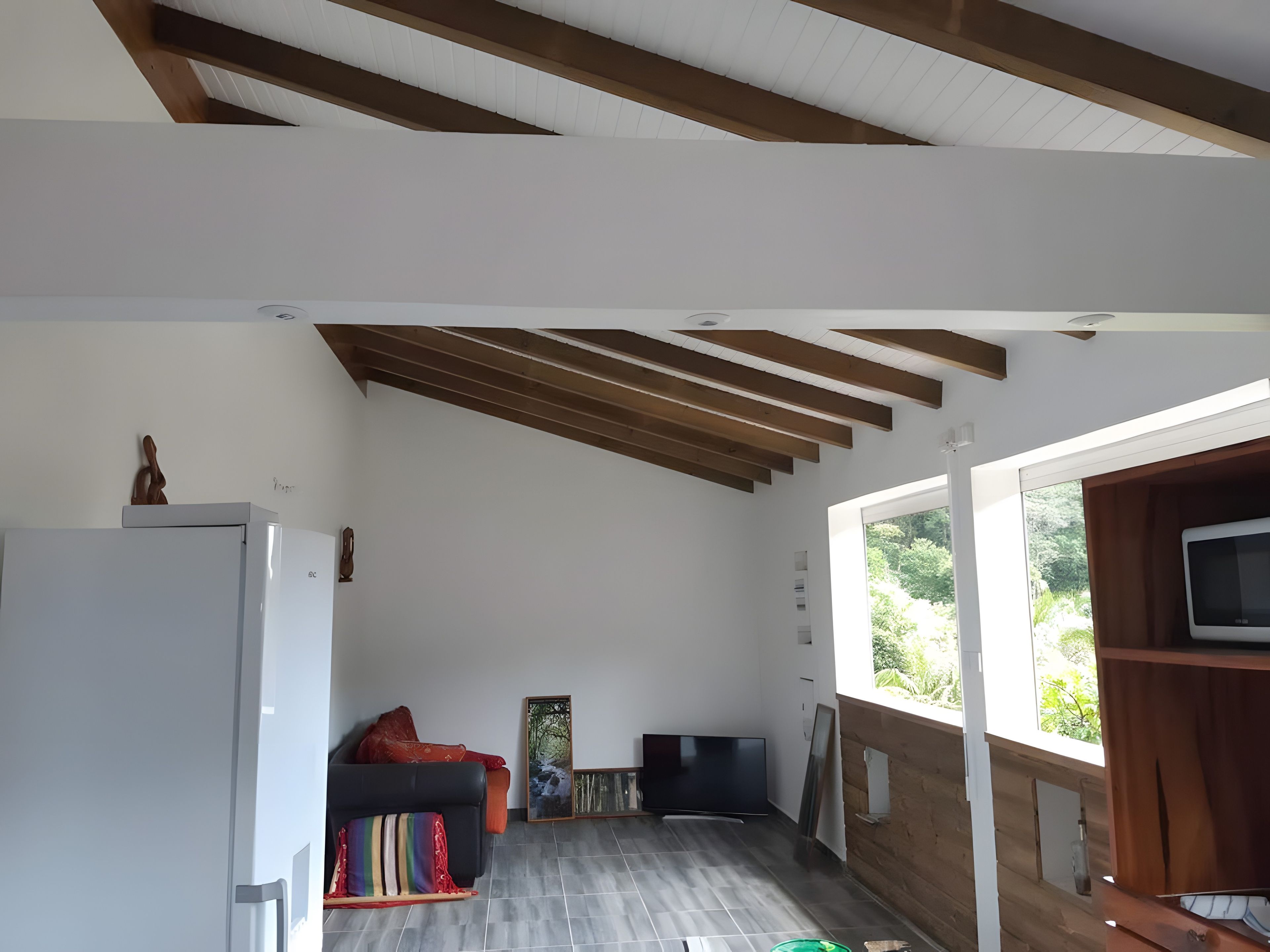 Een moderne woonkamer met een bank, een televisie en een groot raam.