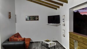 Een moderne woonkamer met een bank, een televisie, een bijzettafeltje en een schilderij aan de muur.