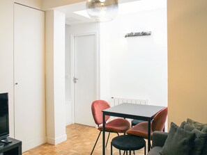 A small, well-lit room with a television, a dining table with chairs, and a sofa. - One-bedroom apartment for 4 guests in Paris 9 (Paris)