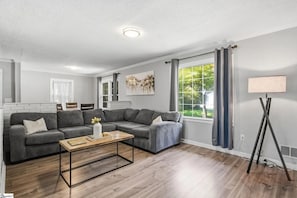 A modern living room with a sectional sofa, a coffee table, and a floor lamp. - Spacious 4-bedroom house in beautiful Taylors - 10 min drive from DT Greenville (Taylors)
