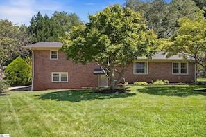 A two-story brick house with a well-maintained lawn and a large tree in front. - Spacious 4-bedroom house in beautiful Taylors - 10 min drive from DT Greenville (Taylors)