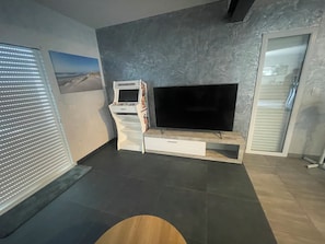 Ein modernes Wohnzimmer mit Flachbildfernseher, Spielkonsole und integriertem Schrank.