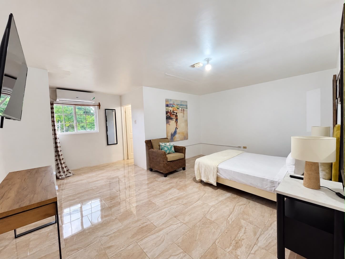 Una habitación de hotel con una cama, un escritorio, una silla, un televisor y un cuadro en la pared.