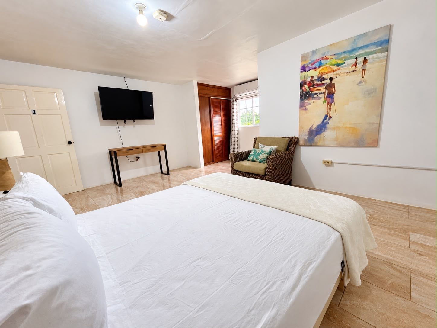 Una camera d'albergo con un letto, una televisione, una sedia e un quadro appeso al muro.