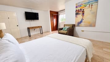 Una camera d'albergo con un letto, una televisione, una sedia e un quadro appeso al muro.