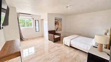 A bedroom with a bed, a chair, a desk, a lamp, and a painting on the wall.