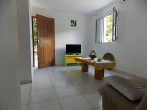 A room with a television on a green stand, a wooden door, a window, and a sofa.