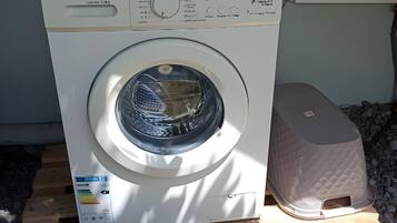 A front-loading washing machine on a wooden pallet, with a control panel and a label indicating it is a Maytag model.