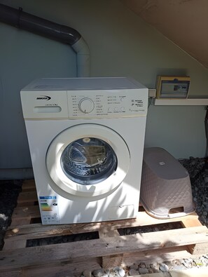 A front-loading washing machine on a wooden pallet, with a control panel and a label indicating it is a Maytag model.